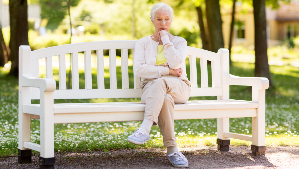 A senior lady sitting on a park bench contemplating if she is eligible for social security survivor benefits.