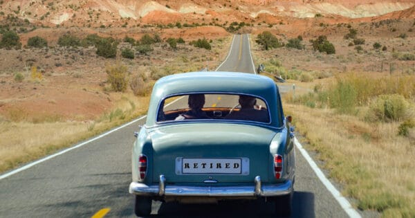 A couple in car with a license plate that says “retired” visiting the desert