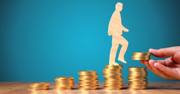 A wooden cutout of a person climbing stacks of coins