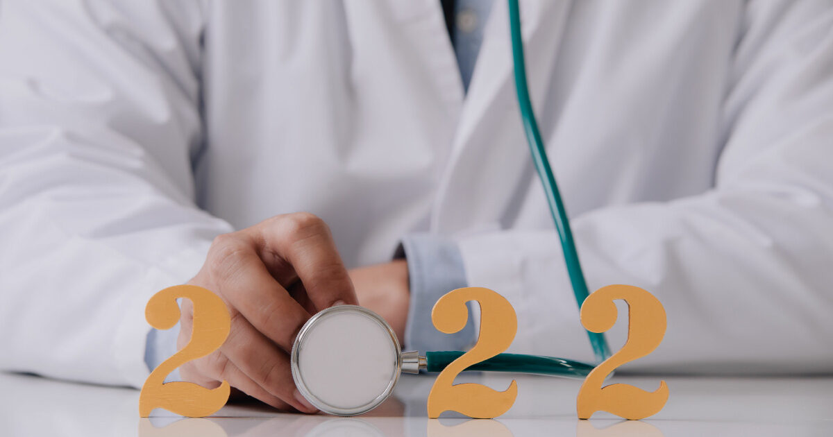 A medical professional holding a stethoscope. The circular end of the scope makes the 0 in the number 2022 meant to represent Medicare updates for 2022