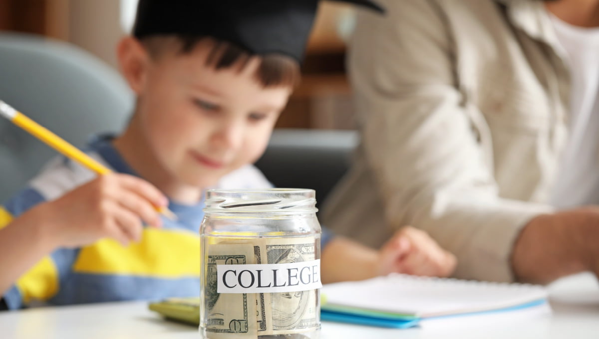A child sitting behind a jar of money with the word college taped on the jar.