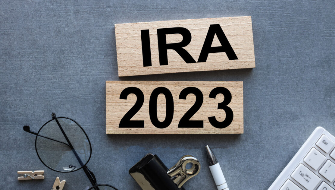 “IRA” and “2023” on wooden signs placed on a desk with various office related items.